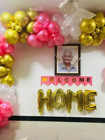 A heartwarming "Welcome Home" decoration. The wall is adorned with a pink and gold balloon garland and foil letters, celebrating a loved one's return.