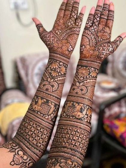 This design features bands of traditional motifs, including elephants and paisleys, creating a rich and textured look that extends up the arms.