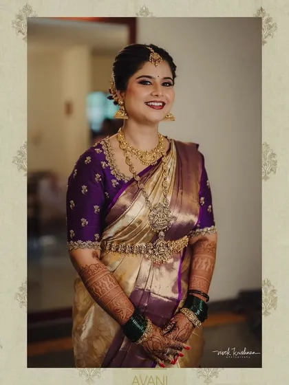 A full-length portrait of the bride in her cream and purple saree, showcasing the elegant combination of colors and the fine craftsmanship of the blouse.
