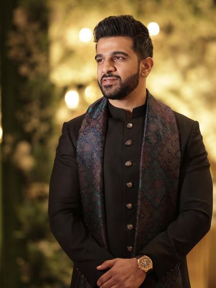 A client looking suave at his sister's wedding in a custom black achkan. I added a printed silk stole to introduce a touch of color and pattern, creating a look of understated luxury.