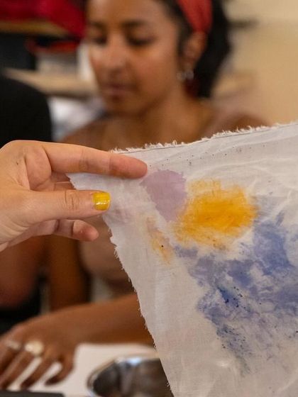 An instructor showing the beautiful colors bleeding onto a paper towel. This simple demonstration reveals the vibrant potential of the botanical inks created during our workshop.
