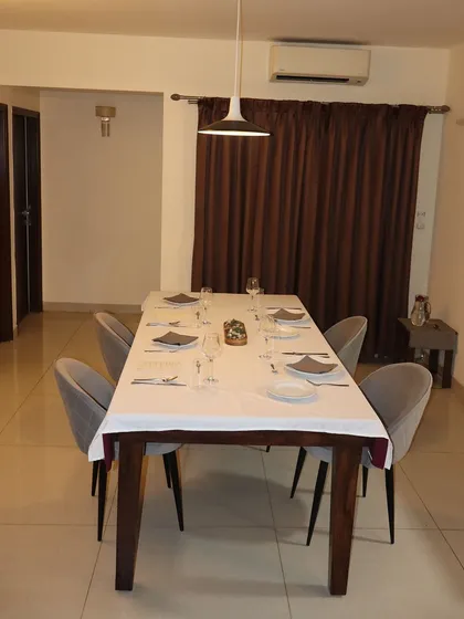 A wide shot of the dining space, ready to welcome guests. The open view into the kitchen allows for an interactive and engaging private dining experience.
