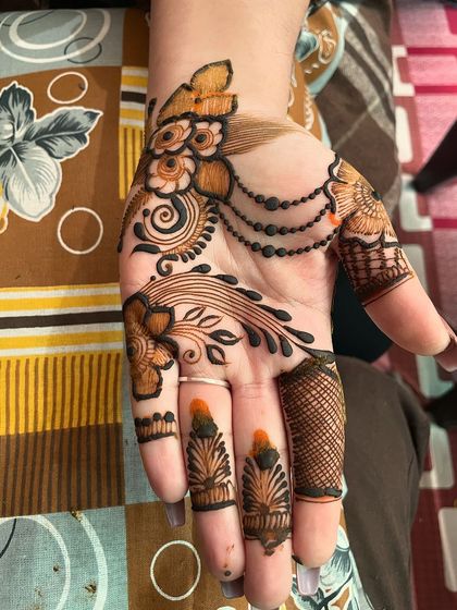 This is a beautiful example of an Arabic-style mehndi design. The pattern flows diagonally across the hand, using a mix of bold lines, delicate chains, and floral art.