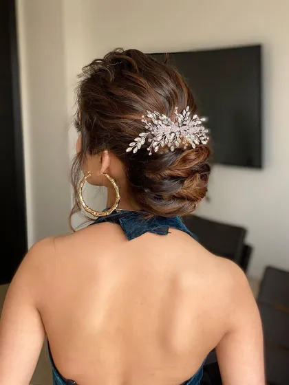 This textured bun is accented with a beautiful silver leaf hair accessory. It's a chic and modern updo, perfect for a cocktail party or a formal evening event.