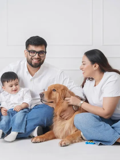 A relaxed family photo session where parents and their baby interact naturally with their golden retriever, creating a candid and loving portrait.