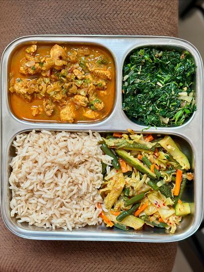 This nutrient-dense plate includes brown rice, chicken curry, and a generous serving of sautéed mixed vegetables and greens.