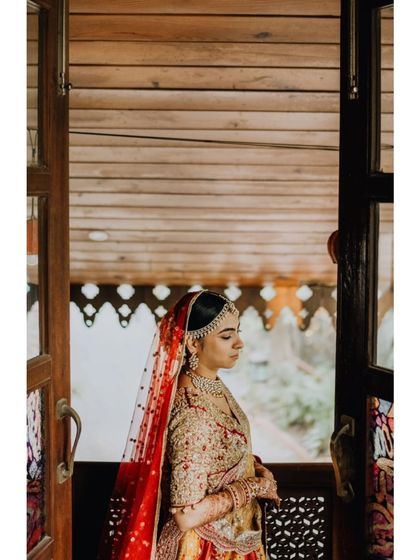 A pensive bridal portrait. The bride stands by a wooden window, a moment of quiet reflection before the ceremony begins.
