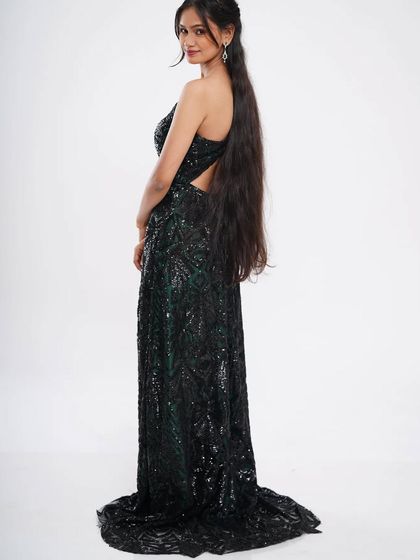 The back view of the black sequin slit gown, showing its elegant open-back design. This is a perfect dress for a red-carpet-themed party or a sophisticated evening event.