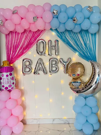A classic "Oh Baby" gender reveal or baby shower decoration. The setup uses pink and blue balloons and streamers to represent a boy or girl, with foil balloons spelling out the message.
