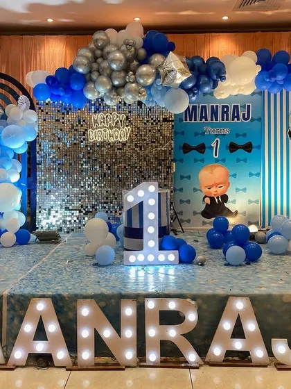 This is a duplicate of ID 89 and 146. A Boss Baby themed first birthday with a shimmer wall. This stage setup combines a popular character theme with a glamorous silver sequin backdrop and large marquee letters.