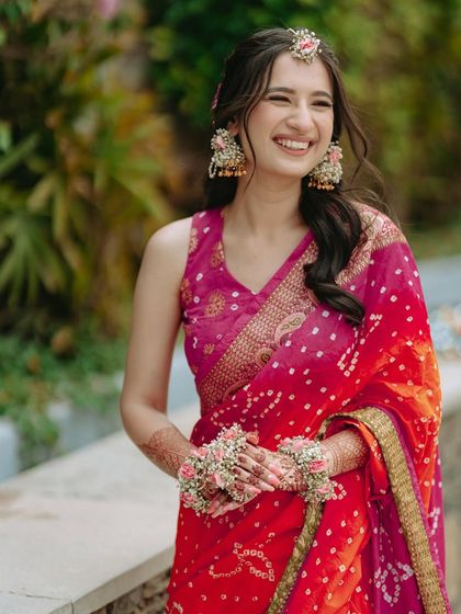The bride's radiant smile, adorned with floral jewelry, perfectly captures the happiness of her Haldi day.