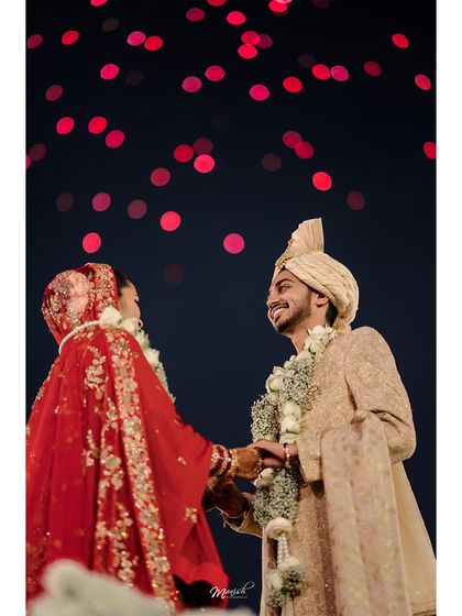 The couple shares a look under a sky of red bokeh lights, a magical and cinematic moment from their wedding night.