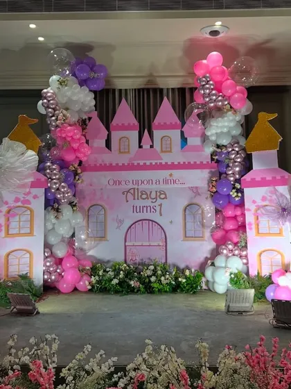 We bring fairy tales to life with our princess castle decorations. This large-scale setup for a first birthday includes custom-built castle facades and towers, surrounded by cascading pink and purple balloons to create a magical kingdom for the little princess.