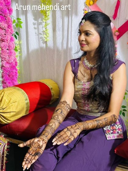 A beautiful bride posing during her mehendi ceremony, with her arms adorned with my custom henna art.