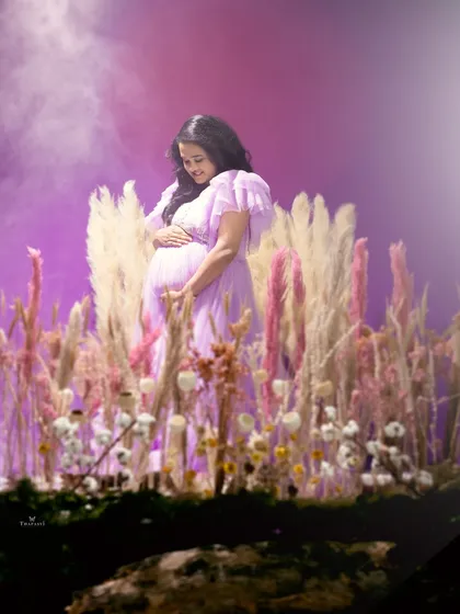 A soft and tender moment captured amidst a dreamy lavender field set. The mother-to-be looks down lovingly at her bump, surrounded by ethereal light.