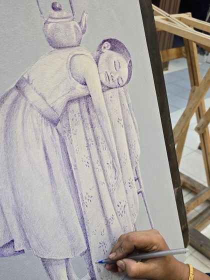 A close-up of the work in progress, showing the artist adding shading to the sleeping figure in her imaginative ballpoint pen piece.