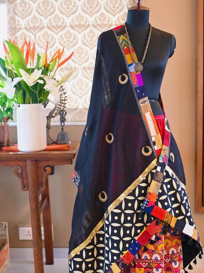 This pure black linen dupatta is a study in contrasts. The lightweight fabric is detailed with a bold, graphic print and a colorful scrap fabric trim, then hand-embroidered with delicate Zardozi 'chaand buti' or moon motifs.