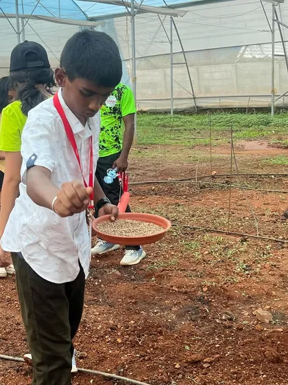 A summer camp participant learns how to sow seeds in the field. These hands-on activities teach responsibility and give children a real sense of accomplishment.