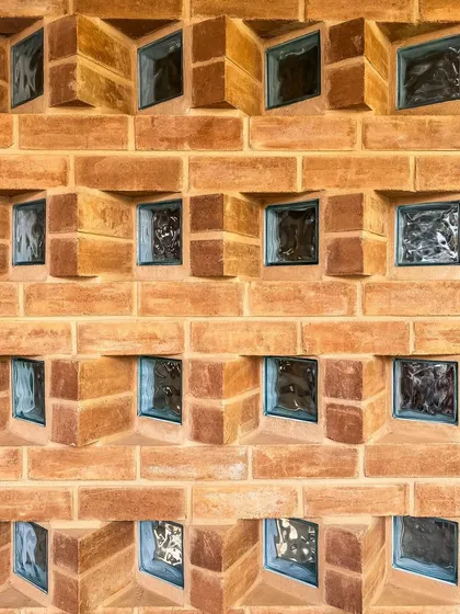 We believe in finding beauty in the details. This is a close-up of a custom jaali wall, where we used angled mud blocks and glass inserts to create a beautiful pattern that plays with light and privacy, casting unique shadows throughout the day.