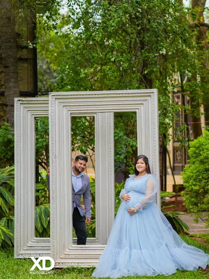 A creative shot using large white picture frames as a prop to frame the couple in a garden.