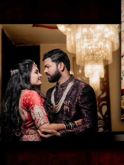 The couple shares a loving gaze during their reception. The grand chandelier in the background adds a touch of glamour to this romantic moment.