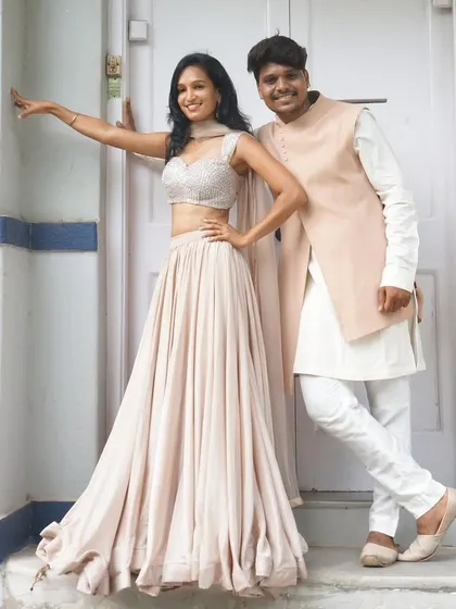 Another great his and her look from our collection. She is wearing a flowing satin lehenga with a sequin blouse, perfectly complemented by his peach bandhgala jacket.