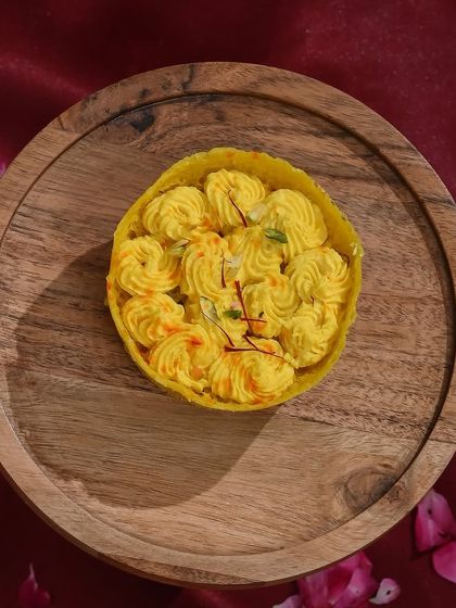 A beautiful saffron-flavoured ghewar, garnished with delicate saffron strands for a rich and aromatic experience.