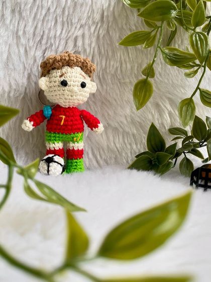 A mini replica doll of the football superstar Cristiano Ronaldo, CR7! This keychain-sized doll is ready for the field with his jersey and a tiny football.