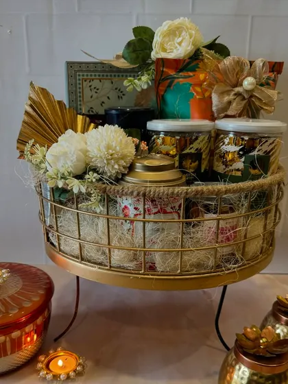 Our metal and jute tray is the perfect combination of sweet treats, namkeen, and festive gifts. This hamper is filled with gourmet jars and decorative items, all beautifully arranged.