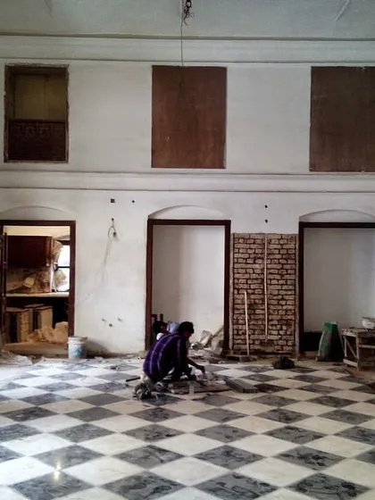 The main hall of a 19th-century haveli in Old Delhi during restoration. This image shows the space being prepared for new flooring, with a craftsman carefully working on the black and white marble pattern.