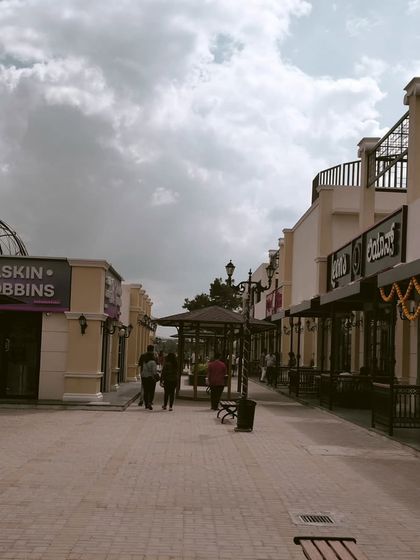 A view down our open-air walkway, with Baskin Robbins and other storefronts visible under a cloudy sky.
