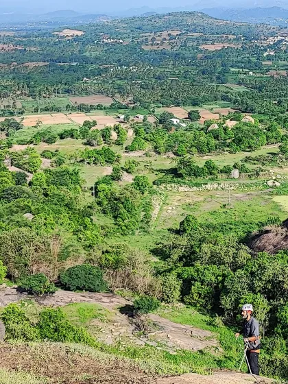 Two climbers on a new route at Hosadurga, with the vast green landscape stretching out below them.