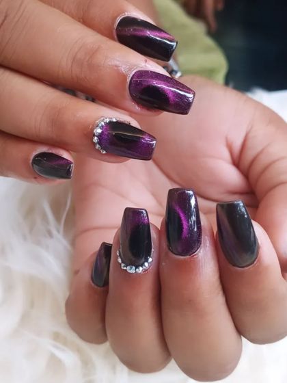 A deep purple cat-eye effect on coffin nails, creating a magnetic, metallic shimmer. Rhinestone accents add an extra touch of sparkle.