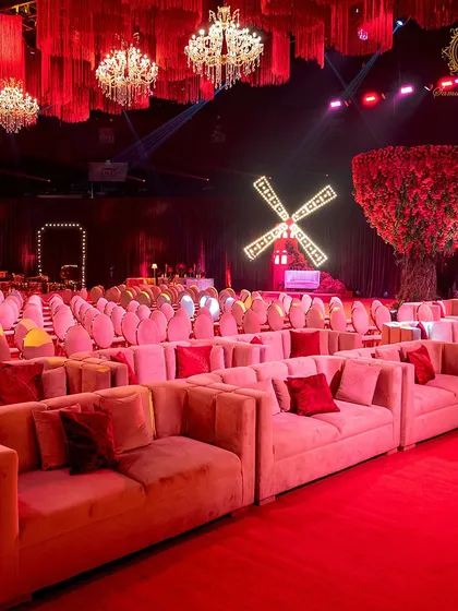 A wide view of the seating arrangement, showing the plush lounge sofas in the foreground and the rows of guest chairs leading towards the stage, with the lit windmill visible in the background.