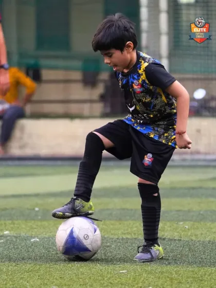 A young player proudly stands with his foot on the ball, a classic pose that shows confidence and control.