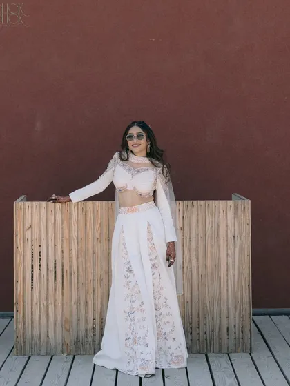 The bride, Krina, looking effortlessly cool at her wedding event in Balotra. Her stylish white outfit and sunglasses are perfect for a sunny, outdoor celebration.