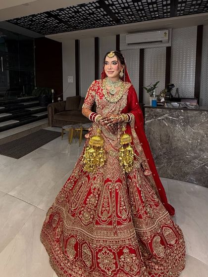 A full-length photo of my beautiful bride, showcasing her magnificent red lehenga and golden kalire. The makeup is kept classic and elegant to complement her traditional Punjabi bridal look.