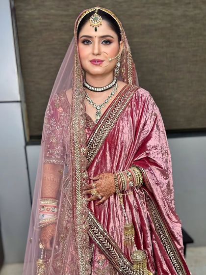 A bride in a beautiful dusty rose velvet lehenga. The makeup is soft and romantic, with a focus on rosy tones.