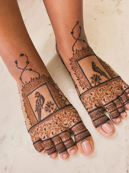 Foot mehndi can be so elegant. This engagement design features a unique parrot motif set within a decorative frame, with delicate chain details extending up the ankle for a beautiful, complete look.