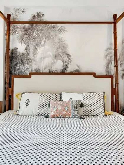 A master bedroom featuring a four-poster bed set against a wall with a subtle, large-scale tropical mural. The design is serene and sophisticated, creating a peaceful retreat.