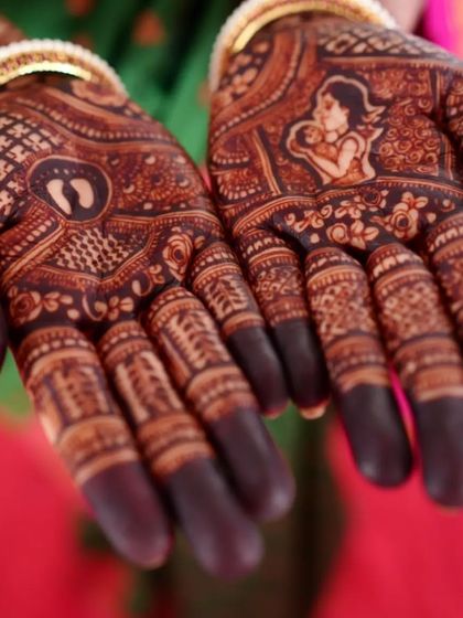 A close-up of the beautiful dark stain on a baby shower mehendi. You can clearly see the details of the mother-and-child portrait and the baby feet motif.