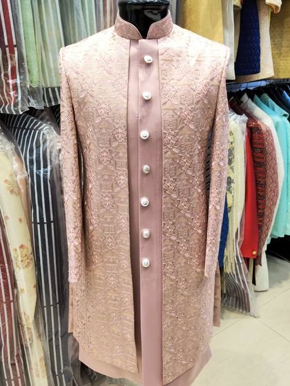 A heavy-embroidered open sherwani in a dusty rose color. The intricate threadwork and layering over a satin kurta make this a standout piece for any groom.