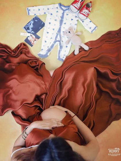 A creative flat-lay concept from the mother's perspective. This artistic shot includes baby clothes, shoes, and ultrasound pictures, creating a beautiful collage of her dreams for the baby.