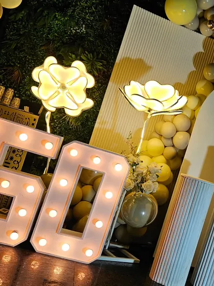 Highlighting the large, light-up '50' marquee numbers and illuminated flower props. These elements add a touch of glamour and are perfect for photos.