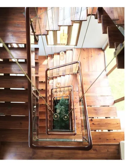 A view looking down the timber and steel staircase of the 'Aangan' house. This project was about creating a warm, biophilic space, and this central feature connects the floors while drawing the eye towards the greenery below.