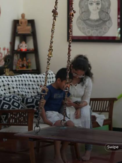 Duplicate of 178. A mother and son share a moment on the indoor swing, which is a central feature of the living area. The swing adds a playful and traditional element to the home.