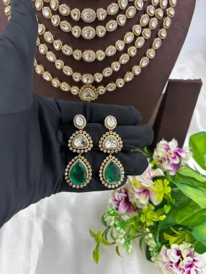 Our multi-layered Rani Haar sets are a bestseller. This piece showcases six layers of uncut Polki-style stones with a stunning emerald green pendant and matching earrings, offering a truly royal look for weddings and grand occasions.