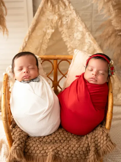 A beautiful portrait of newborn twins, a boy and a girl, swaddled and sleeping side by side in a rustic cane bed. We have experience safely posing and photographing multiples.