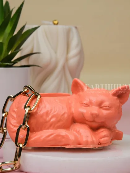 A close-up of the peach-colored cat planter. The smooth, stone-like finish of the Jesmonite gives it a high-quality feel.