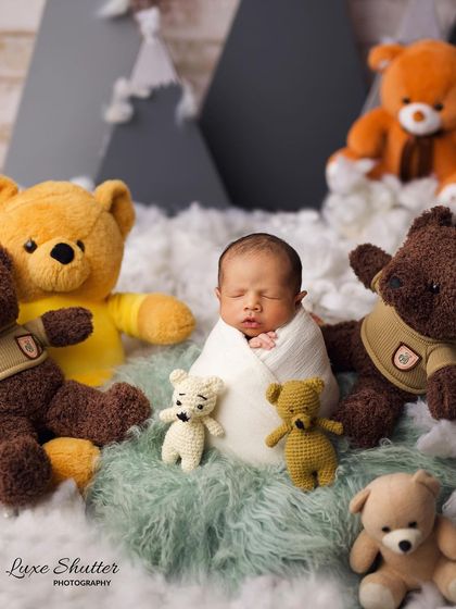 A fun and adorable setup where the newborn is surrounded by a whole family of teddy bears.
